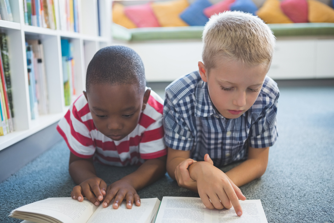 School kids reading book in library